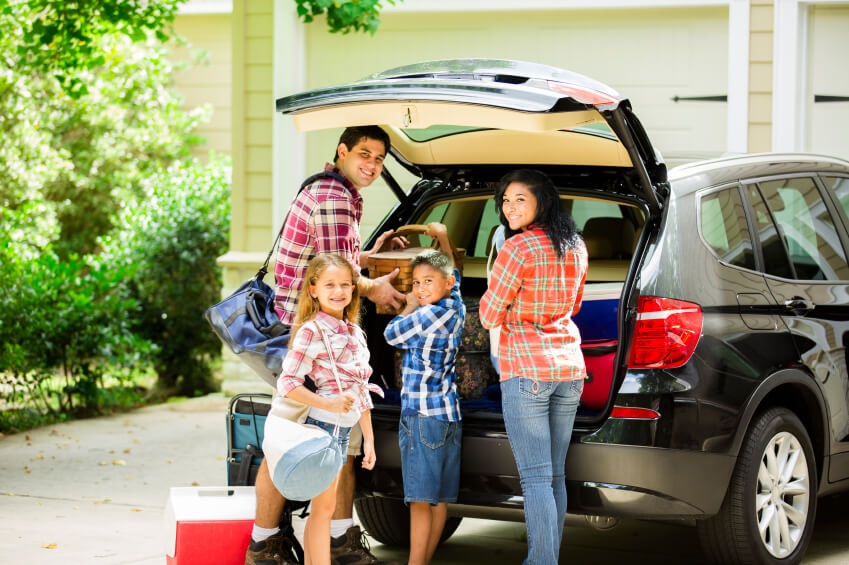 Family with two kids loading the car for a road trip